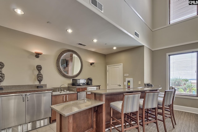 601 Main St Unit 518, Columbia, SC 29201 - kitchen featuring healthy amount of natural light, brown cabinetry, a breakfast bar area, light stone counters, and recessed lighting