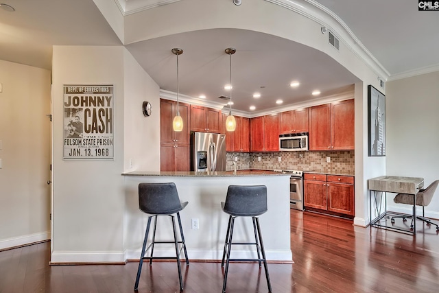 601 Main St Unit 518, Columbia, SC 29201 - kitchen with appliances with stainless steel finishes, a peninsula, a breakfast bar, tasteful backsplash, and dark wood-style flooring