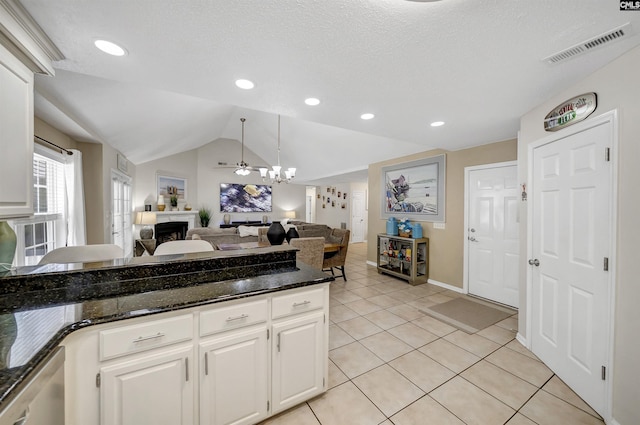 614 Beech Branch Dr, Irmo, SC 29063 - kitchen featuring a fireplace, open floor plan, vaulted ceiling, dark stone countertops, and white cabinetry