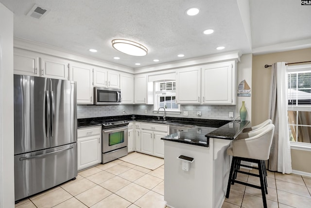 614 Beech Branch Dr, Irmo, SC 29063 - kitchen featuring appliances with stainless steel finishes, a peninsula, white cabinets, decorative backsplash, and recessed lighting
