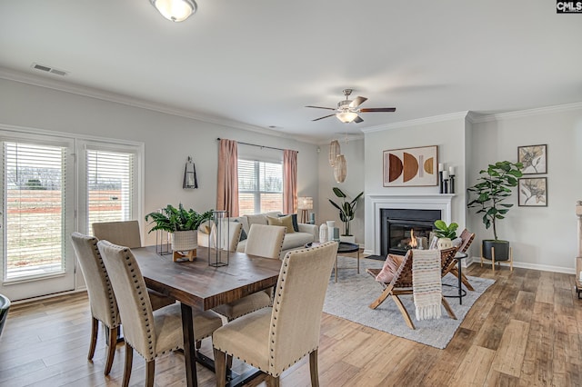 2095 County Line Trl, Elgin, SC 29045 - dining space featuring crown molding, light wood finished floors, a glass covered fireplace, and a ceiling fan