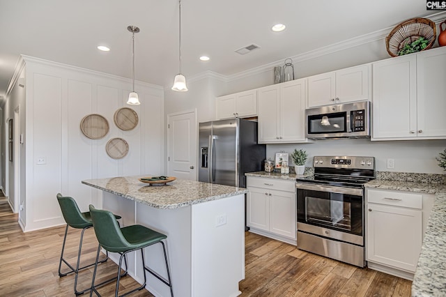 2095 County Line Trl, Elgin, SC 29045 - kitchen featuring stainless steel appliances, a center island, ornamental molding, white cabinetry, and light wood finished floors