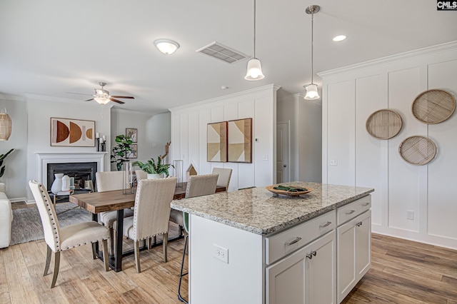2095 County Line Trl, Elgin, SC 29045 - kitchen featuring ceiling fan, crown molding, a glass covered fireplace, a kitchen island, and decorative light fixtures