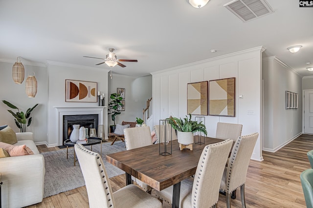 2095 County Line Trl, Elgin, SC 29045 - dining space with crown molding, light wood-style floors, ceiling fan, stairway, and a premium fireplace