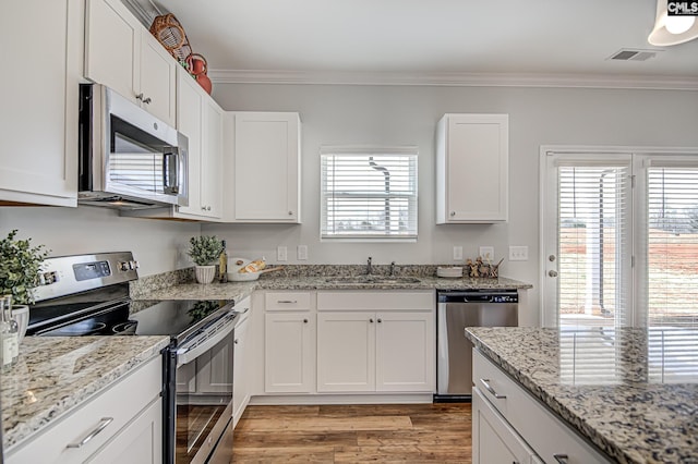 2095 County Line Trl, Elgin, SC 29045 - kitchen featuring appliances with stainless steel finishes, light wood-type flooring, ornamental molding, white cabinets, and light stone counters