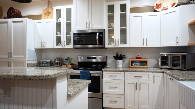 2367 Mount Pilgrim Church Rd, Prosperity, SC 29127 - kitchen with appliances with stainless steel finishes, white cabinets, decorative backsplash, glass insert cabinets, and light stone countertops