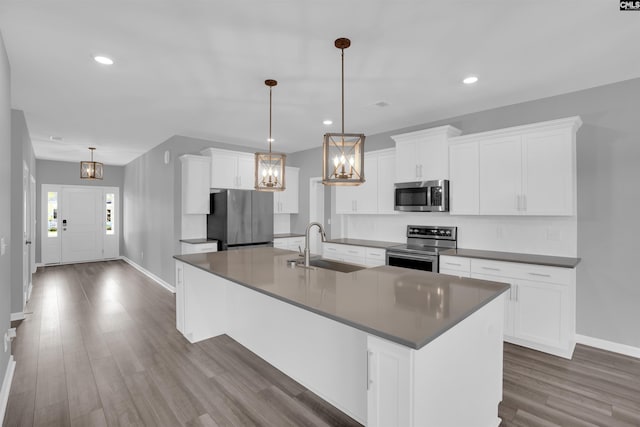 4040 Summerland Way, Elgin, SC 29045 - kitchen featuring appliances with stainless steel finishes, dark countertops, dark wood-type flooring, an island with sink, and white cabinets