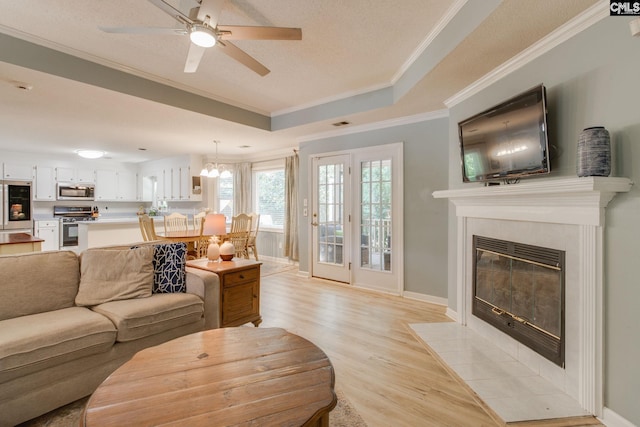 112 Pebble Place Ct, Lexington, SC 29072 - living area featuring a tray ceiling, light wood-style flooring, ornamental molding, a ceiling fan, and a tiled fireplace