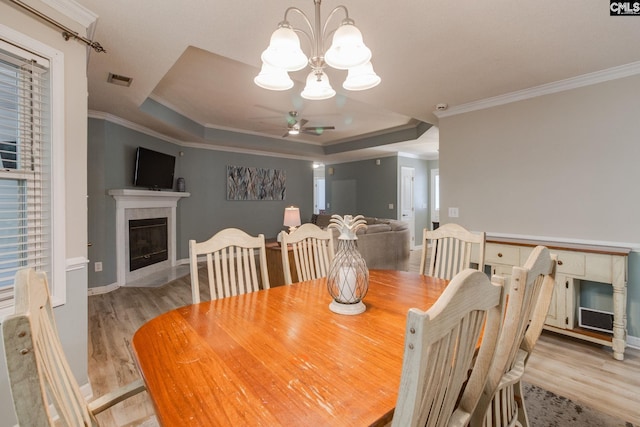112 Pebble Place Ct, Lexington, SC 29072 - dining area featuring a fireplace, a ceiling fan, a raised ceiling, light wood finished floors, and a chandelier