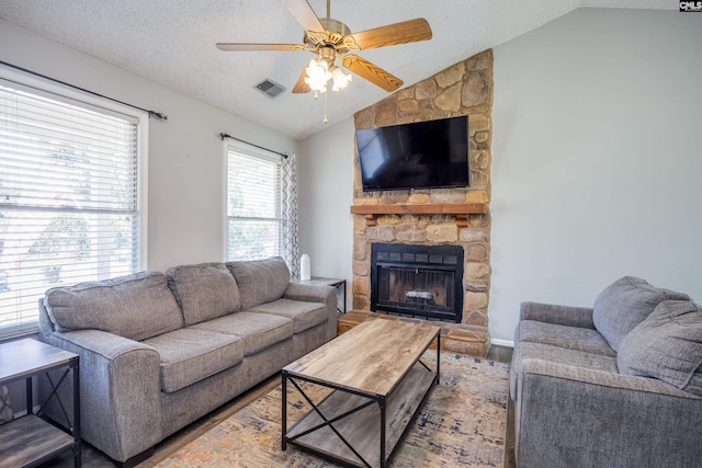 1426 B Ave, West Columbia, SC 29169 - living room with lofted ceiling, wood finished floors, a ceiling fan, a stone fireplace, and a textured ceiling