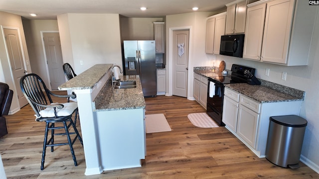 255 Common Reed Dr, Gilbert, SC 29054 - kitchen featuring black appliances, light wood-style floors, a kitchen breakfast bar, a center island with sink, and recessed lighting