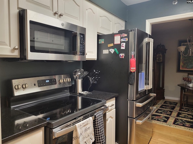 910 Poinsett Pl Unit 3, West Columbia, SC 29169 - kitchen with appliances with stainless steel finishes, white cabinetry, wood finished floors, and dark stone counters
