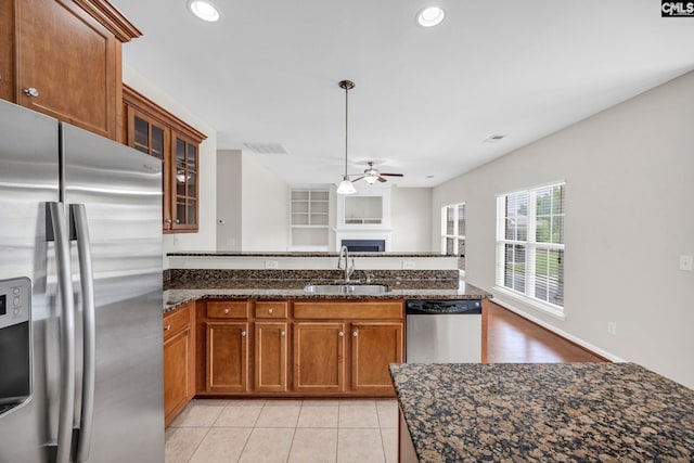 267 Caedmons Creek Dr, Irmo, SC 29063 - kitchen with appliances with stainless steel finishes, a ceiling fan, a fireplace, brown cabinetry, and dark stone countertops