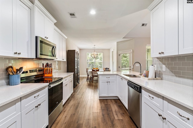 2203 Newberry Landing Cir, Newberry, SC 29108 - kitchen featuring appliances with stainless steel finishes, a peninsula, dark wood-type flooring, white cabinetry, and tasteful backsplash