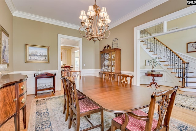 3450 Summerland Hwy, Leesville, SC 29070 - dining space featuring light wood-style floors, ornamental molding, a chandelier, stairs, and a wainscoted wall
