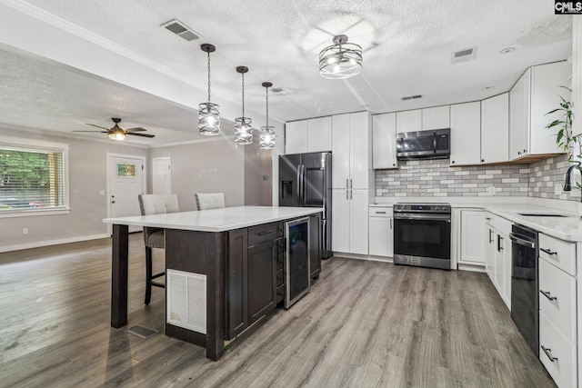 2032 Pinewood St, Cayce, SC 29033 - kitchen with appliances with stainless steel finishes, wine cooler, a textured ceiling, wood finished floors, and tasteful backsplash
