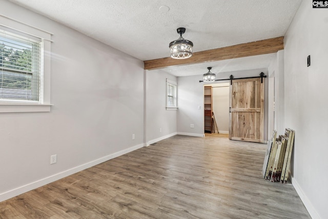 2032 Pinewood St, Cayce, SC 29033 - spare room featuring a barn door, a textured ceiling, beamed ceiling, and wood finished floors