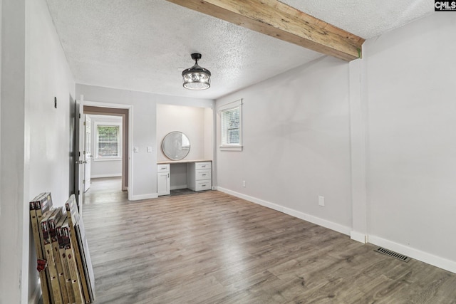 2032 Pinewood St, Cayce, SC 29033 - unfurnished living room with a textured ceiling, plenty of natural light, light wood-style floors, and beamed ceiling