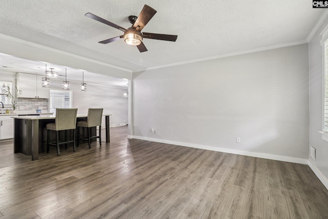 2032 Pinewood St, Cayce, SC 29033 - unfurnished living room with ceiling fan, dark wood-type flooring, ornamental molding, and a textured ceiling