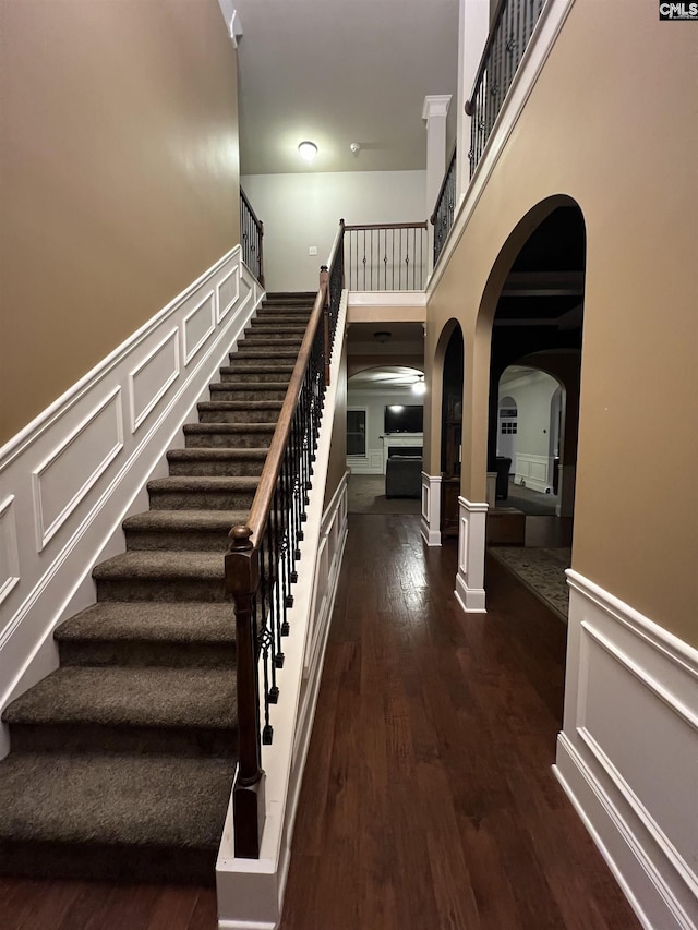 127 Brooklet Dr, Lexington, SC 29072 - staircase featuring arched walkways, wood finished floors, wainscoting, a decorative wall, and a high ceiling