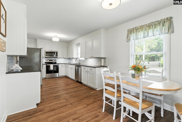 1159 Starview Dr, West Columbia, SC 29172 - kitchen featuring appliances with stainless steel finishes, tasteful backsplash, dark wood finished floors, dark countertops, and ornamental molding