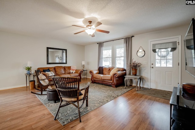 living room featuring light hardwood / wood-style floors, a textured ceiling, ceiling fan, and a wealth of natural light