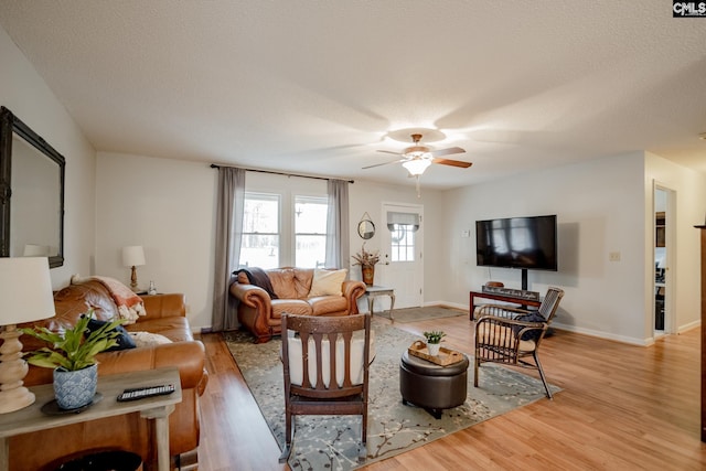 living room with light hardwood / wood-style floors, ceiling fan, and a textured ceiling