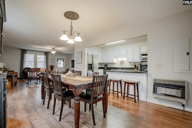 dining area with sink, light wood-type flooring, and ceiling fan with notable chandelier