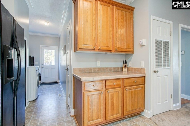 kitchen featuring light tile flooring, tile countertops, ornamental molding, and black fridge with ice dispenser