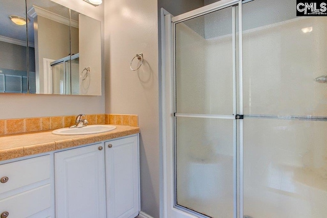 bathroom with ornamental molding, vanity, and an enclosed shower