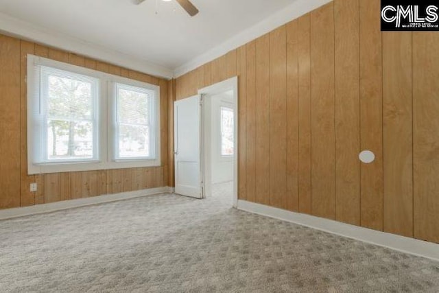 unfurnished bedroom with wooden walls, light carpet, and ceiling fan