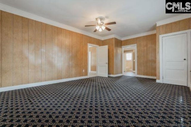 unfurnished room featuring wooden walls, crown molding, and ceiling fan