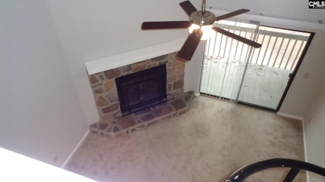 unfurnished living room featuring ceiling fan, a stone fireplace, and carpet