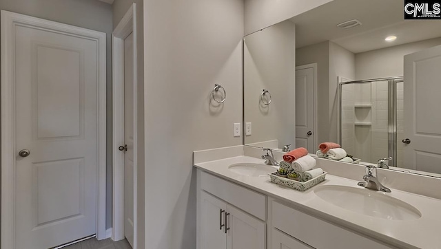 bathroom featuring an enclosed shower, dual sinks, and large vanity