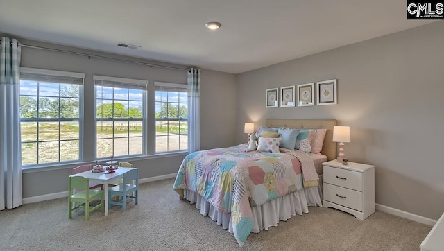 bedroom featuring light colored carpet and multiple windows