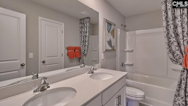 full bathroom with double sink, toilet, large vanity, and shower / tub combination