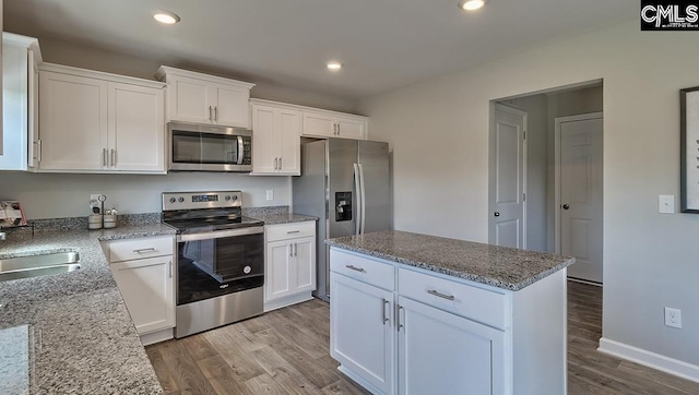 kitchen with white cabinets, appliances with stainless steel finishes, and light hardwood / wood-style flooring