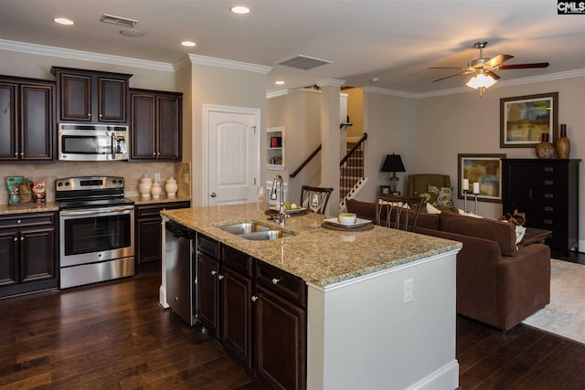 kitchen with an island with sink, ceiling fan, stainless steel appliances, sink, and dark hardwood / wood-style floors