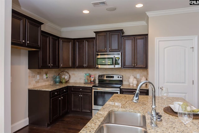 kitchen featuring light stone counters, backsplash, stainless steel appliances, ornamental molding, and dark hardwood / wood-style floors