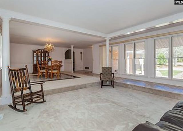 sitting room featuring an inviting chandelier, decorative columns, and light colored carpet