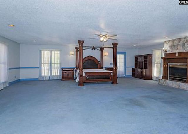 bedroom with carpet flooring, a textured ceiling, and a fireplace