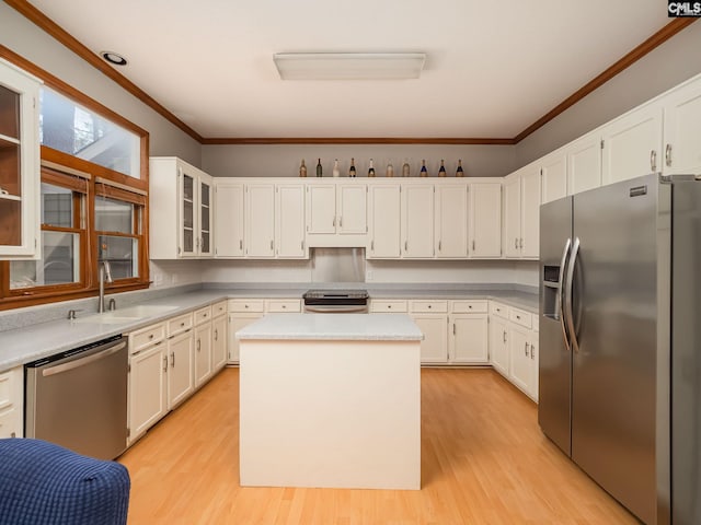 kitchen with appliances with stainless steel finishes, a kitchen island, sink, white cabinetry, and light hardwood / wood-style flooring