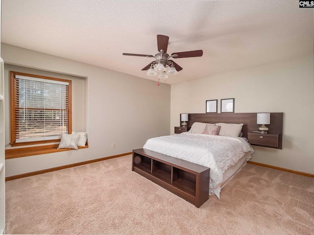 bedroom with light colored carpet, ceiling fan, and a textured ceiling