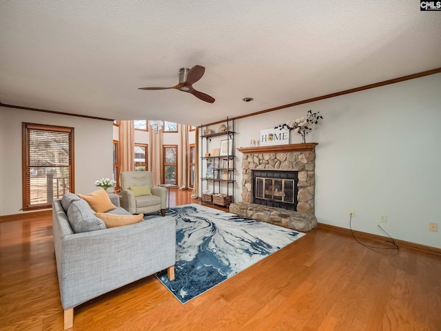 living room with ceiling fan, ornamental molding, a fireplace, and hardwood / wood-style floors