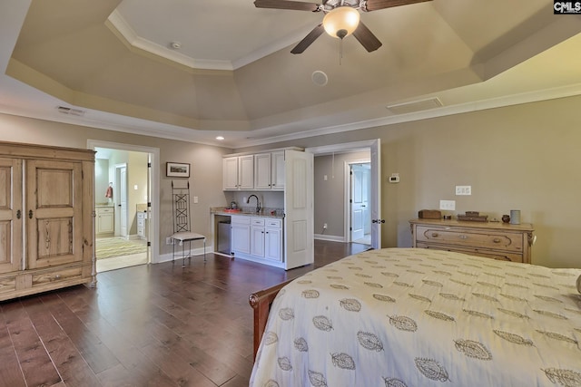 bedroom with ceiling fan, dark wood-type flooring, a raised ceiling, and ensuite bathroom