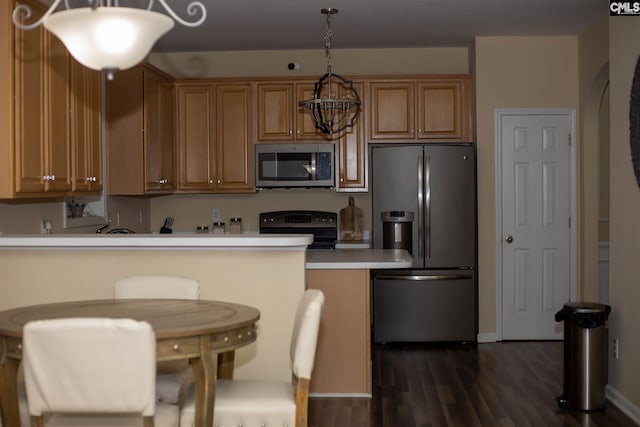 kitchen featuring stainless steel appliances, a breakfast bar, decorative light fixtures, and dark wood-type flooring