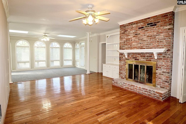 unfurnished living room with ceiling fan, dark hardwood / wood-style floors, a brick fireplace, and crown molding