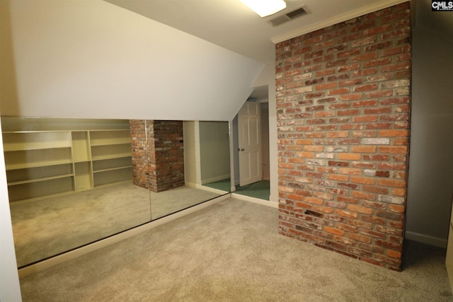 unfurnished bedroom featuring brick wall, light carpet, and vaulted ceiling