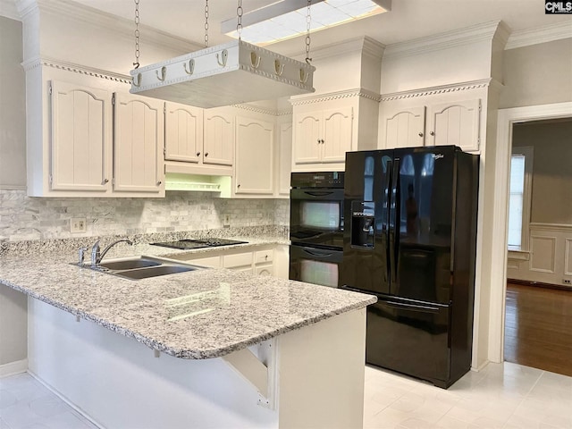 kitchen with hanging light fixtures, backsplash, sink, light hardwood / wood-style flooring, and black appliances