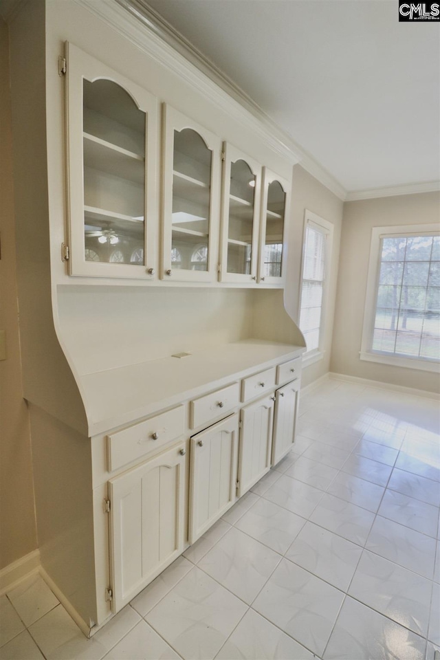 kitchen with ornamental molding, white cabinetry, and light tile floors